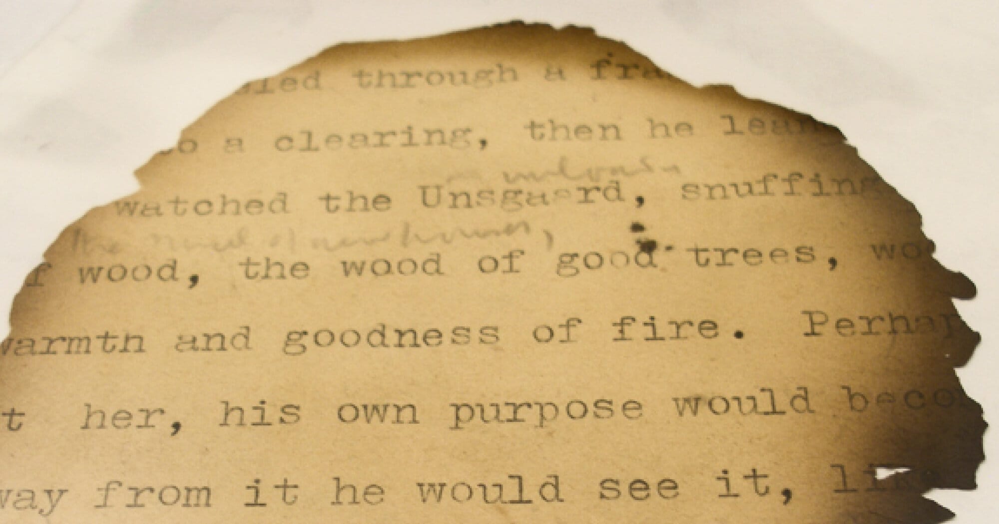 Photograph showing a typescript fragment of Malcolm Lowry's 'In Ballast to the White Sea', with charred edges. The words 