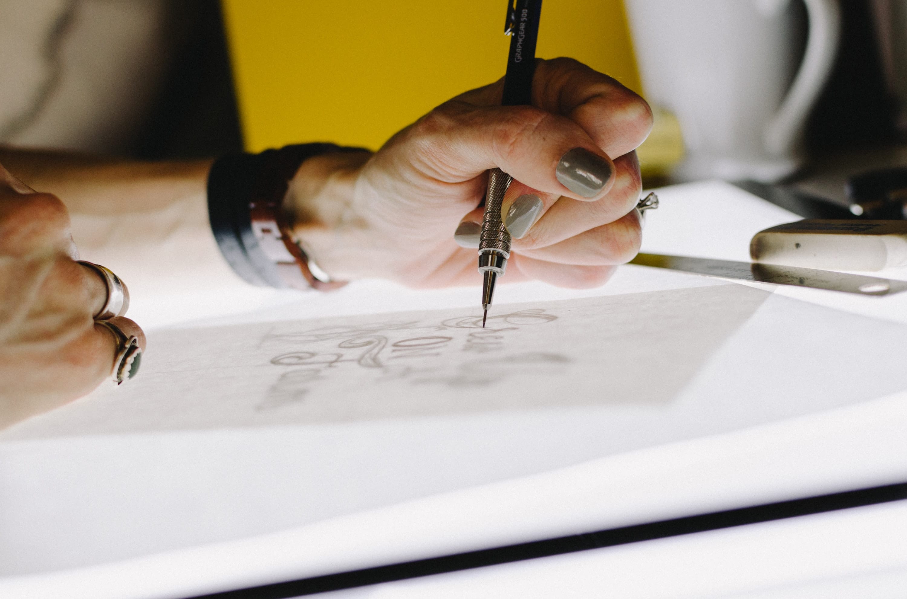 close-up shot of person drawing with graphics pencil on a tracing table