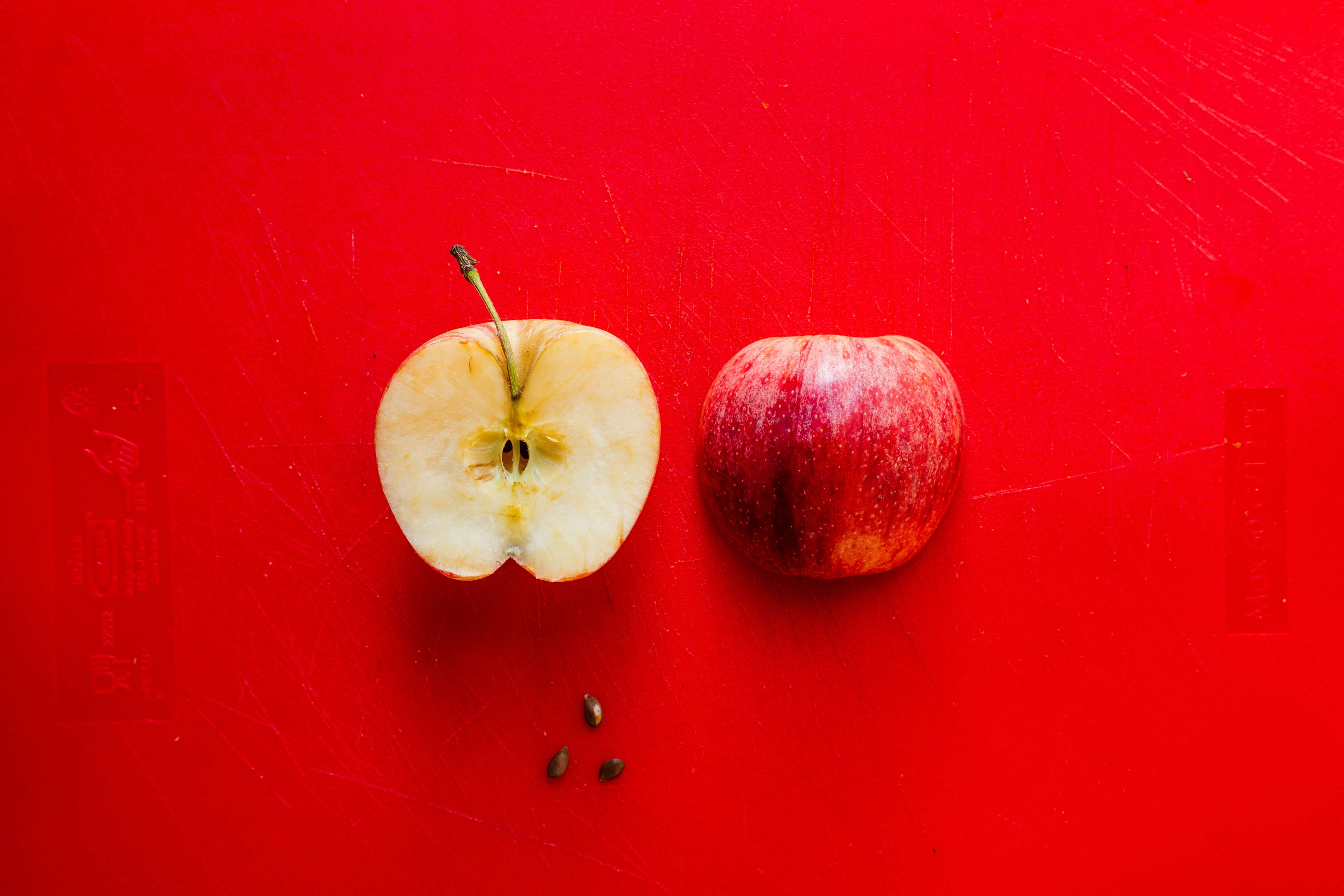 red apple cut in half on top of a red background