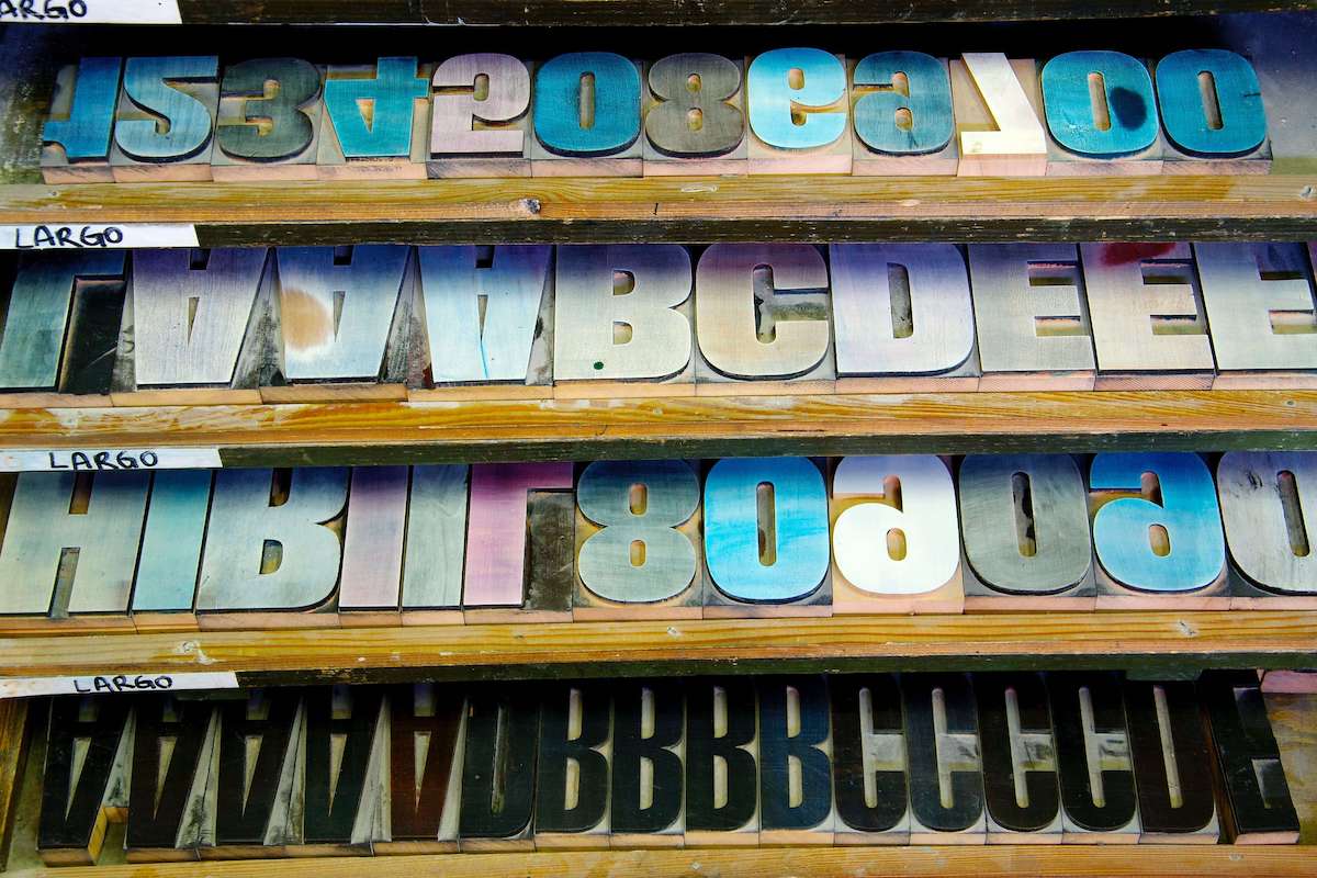 A shelf with old letterpress letters on it that have been dyed different colors over time.